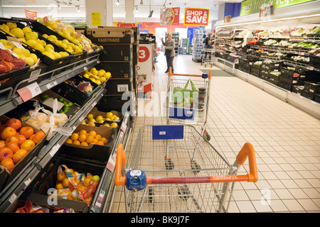 Un trolley e gli acquirenti della frutta e della verdura, corridoio supermercato Sainsburys Foto Stock