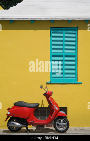 Red scooter contro un luminoso edificio giallo in St George, Bermuda. Foto Stock