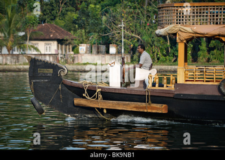 Houseboat capitano dello sterzo kettuvallam la sua barca in lagune del Kerala, India. Foto Stock