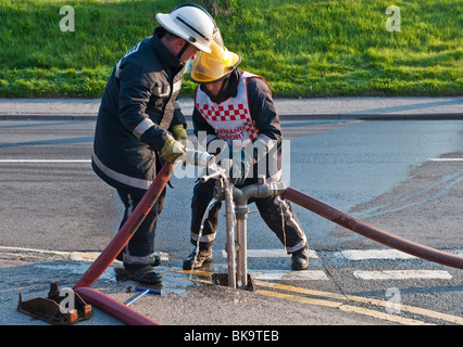 Due vigili del fuoco dalla Mid-Wales fuoco e il servizio di soccorso collegare i tubi flessibili a un idrante di strada Foto Stock
