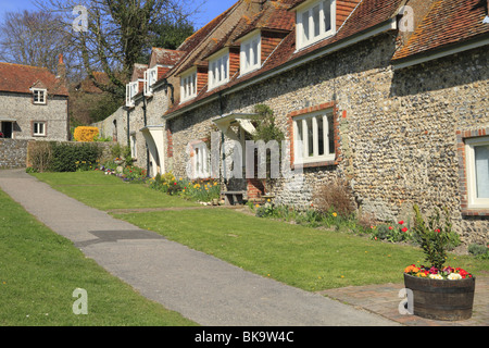 Una terrazza di tradizionali case di pietra focaia, che si affacciano sul verde villaggio a est del decano, East Sussex Foto Stock