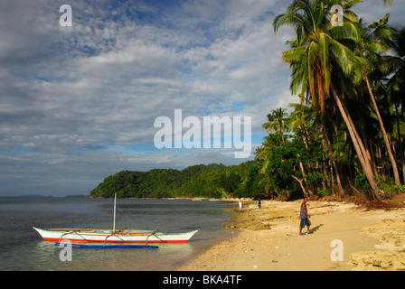 Barca e boatsman sulla spiaggia, El Nido, PALAWAN FILIPPINE, sud-est asiatico Foto Stock