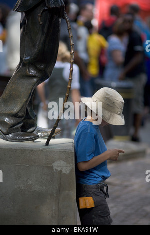 Bambino di nove anni sta sotto la statua di Charlie Chaplin Leicester Square Londra Foto Stock