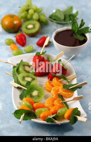 Gli spiedini di frutta con cioccolato e menta. Ricetta disponibile. Foto Stock