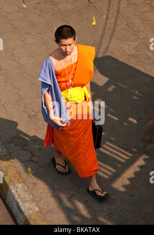 Monaco buddista con gli auricolari di iPod e computer laptop caso; Chiang Mai, Thailandia. Foto Stock