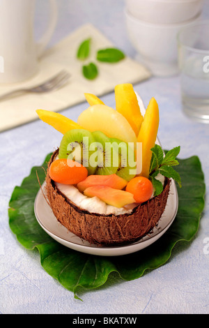 Una insalata di frutta tropicale in una noce di cocco. Ricetta disponibile. Foto Stock