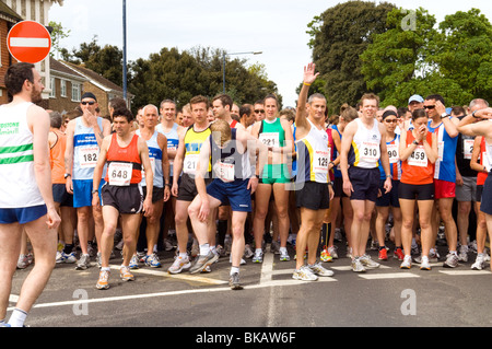 I gruppi di raccolta di guide in strada prima di iniziare a 10km di corsa di beneficenza e con il loro 10k i numeri di gara che mostra. Foto Stock