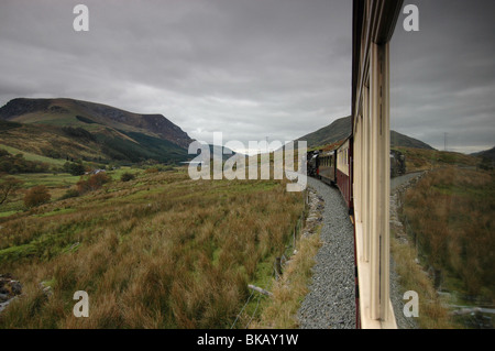 Vista da un carrello con la riflessione sul Welsh Highland preverved ferrovia presso Snnowdon in Snowdonia, Galles. Foto Stock