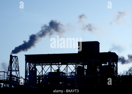 Retroilluminazione industria petrolchimica fumo smog su sky Foto Stock