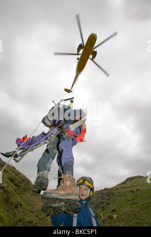 Un mare di RAF re elicottero argano un ferito da un soccorso alpino casualty sito su loughrigg nel distretto del Lago Foto Stock