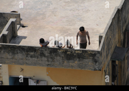 Tre bambini guardando in giù alle loro vittime da balconi in varanasi in India durante Holi festival, il festival del colore Foto Stock