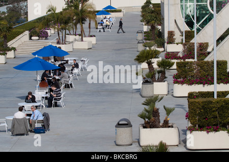 Le persone che hanno preso una pausa seduti ai tavoli fuori San Diego Convention Center Foto Stock