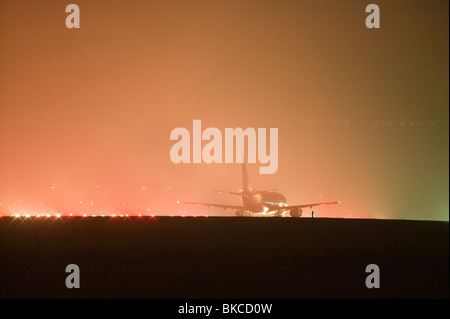 Un piano sulla pista di East Midlands Airport in condizioni di nebbia Foto Stock