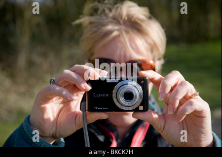 Donna che utilizza una fotocamera digitale compatta per scattare una fotografia. Foto Stock