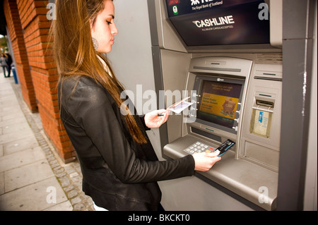 Ragazza adolescente presso ATM cash point machine con denaro di disegno Foto Stock