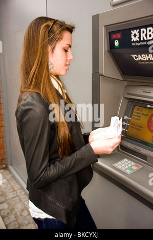 Ragazza adolescente presso ATM cash point machine con denaro di disegno Foto Stock