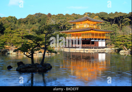 Il padiglione dorato del Kinkakuji tempio di Kyoto, con il suo riflesso nell'acqua del lago circostante su inizio mattina di sole. Foto Stock