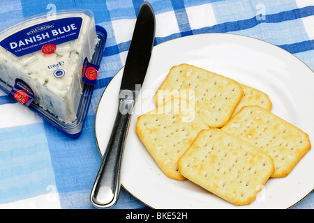Cinque TUC cracker su una piastra bianca con un pacco di danese formaggio blu e coltello Foto Stock