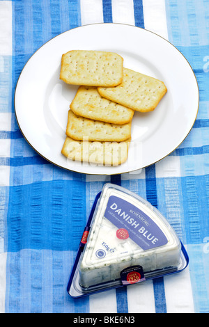 Cinque Tuc cracker su una piastra bianca con un pacco di danese formaggio blu Foto Stock