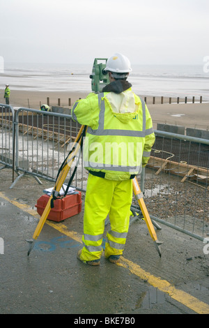 Workman utilizzando un teodolite alluvione dymchurch difesa sul progetto alla costa del Kent Foto Stock
