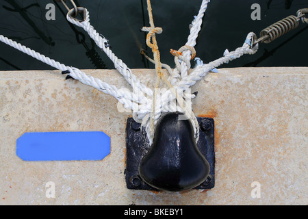 Bollard nero con molte corde nautiche intorno Foto Stock