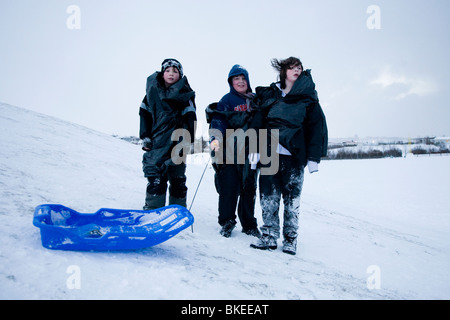 Tre ragazzi in posa per la telecamera nella neve, Hafnarfjordur, una maggiore area di Reykjavik, Islanda Foto Stock