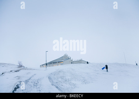 Due ragazzi che giocano sulla neve, Vidistadakirkja chiesa in background. Hafnarfjordur, una maggiore area di Reykjavik, Islanda Foto Stock