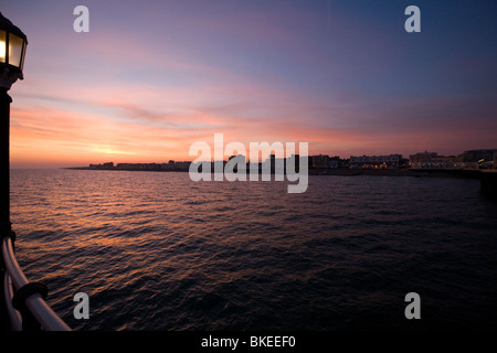 Arancione e rosa bagliore del tramonto su Worthing lungomare da Pier Foto Stock