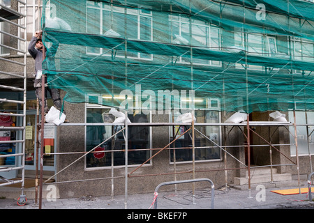 Lavoratore in piedi sul ponteggio al di fuori di una casa che viene riparato. Reykjavik Islanda Foto Stock