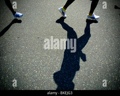 Ombre di runner per le gambe mentre competere nella maratona corsa su strada. Foto Stock