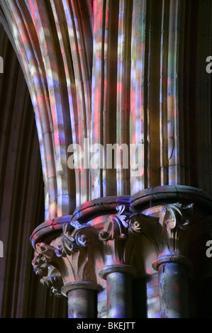 Luce da finestre di vetro macchiate su pilastri in Lincoln Cathedral Regno Unito Foto Stock