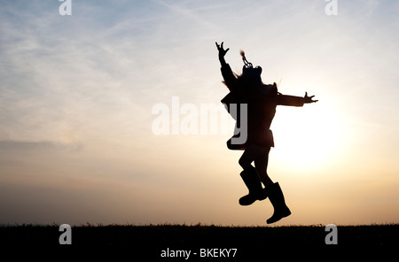 Ragazza giovane energeticamente divertirsi saltando intorno a. Silhouette Foto Stock