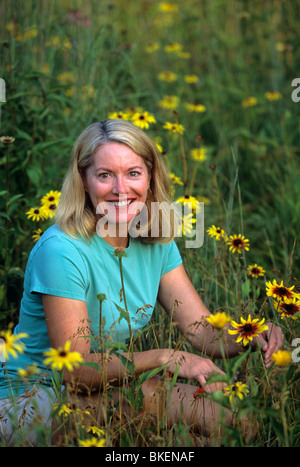 Bionda donna nel suo giardino delle farfalle di RUDBECKIA IN rurale Minnesota. L'estate. Foto Stock