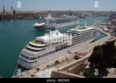 Mediterraneo viaggi e turismo di massa. La nave da crociera Silver Whisper ormeggiata in Malta il Grand Harbour, con il norvegese Gem uscire Foto Stock