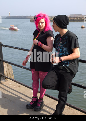Una giovane coppia appoggiata sulla rampa del porto alla biennale festival Goth a Whitby Foto Stock