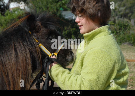 Ragazza, di anni 11, in giardino con il suo animale domestico Falabella cavalli in miniatura. Foto Stock