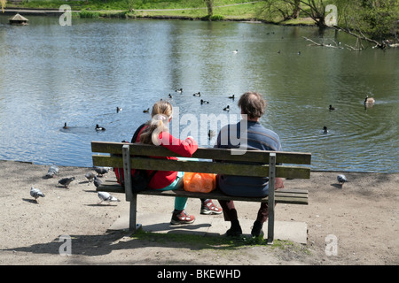 Una coppia di mezza età seduta su una panchina dar da mangiare alle anatre, Chislehurst stagni, Kent REGNO UNITO Foto Stock