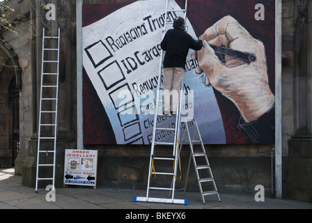 Un murale essendo dipinta su un muro della chiesa commentando i temi delle prossime elezioni nel Regno Unito. Foto Stock