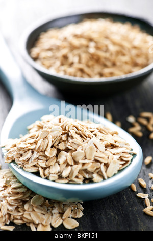 Fiocchi d'avena ammucchiati su un cucchiaio intero e di semole e semolini di avena Foto Stock