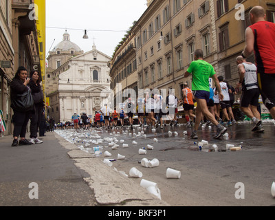 Gli spettatori e corridori al 2010 Maratona di Roma, lazio, Italy con un sacco di plastica vuota tazze di acqua sulla strada Foto Stock