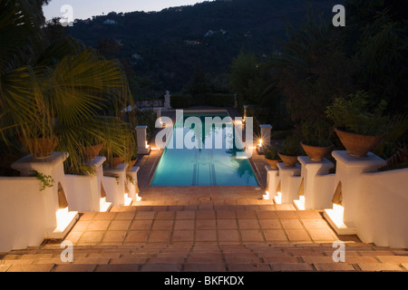 Illumina le fasi che conducono alla piscina illuminata di notte nei giardini di villa nel sud della Spagna Foto Stock