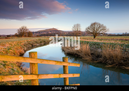 La prima luce del mattino a Glastonbury Tor visto dal fiume Brue sui livelli di Somerset, Glastonbury, Somerset, Inghilterra. Foto Stock