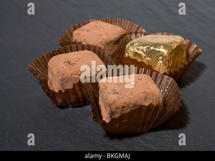 Il lusso del commercio equo Champagne tartufi di cioccolato, spolverato con polvere di cacao su ardesia scuro dello sfondo. Foto Stock