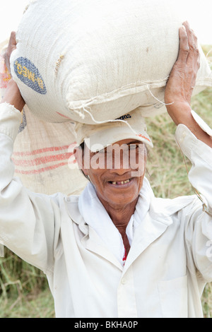 Il vecchio uomo che trasportano il sacco di riso sul suo capo; Batangas; Luzon meridionale; Filippine Foto Stock