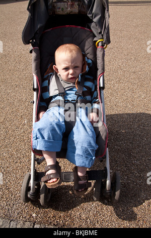 Baby boy (1 anno di età) in un passeggino cercando annoiato. Foto Stock