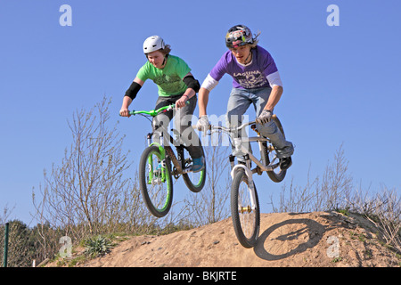 Due teenager jumping insieme con le loro biciclette Foto Stock