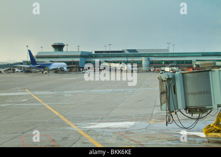 La pista di atterraggio in un aeroporto, che mostra la parte posteriore di un aereo di passeggero in background con un vuoto che porta in primo piano. Foto Stock