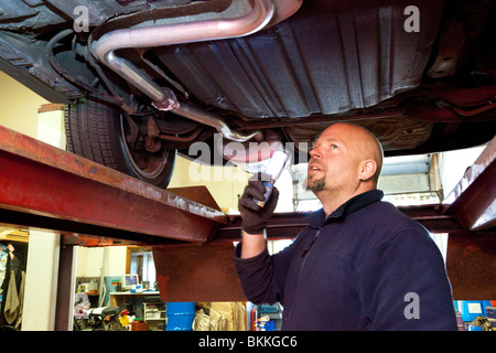 Autofficina controllando la parte inferiore di un auto durante un MOT test nel Regno Unito Foto Stock