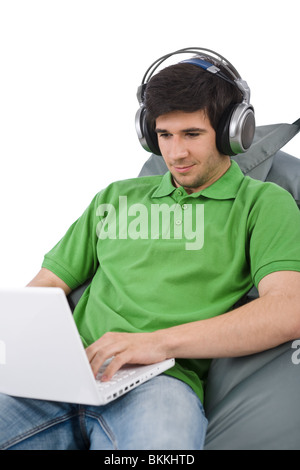 Giovane Uomo con laptop e le cuffie udienza del bean bag su sfondo bianco Foto Stock