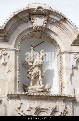 Una statua di San Michele di calpestare Satana entro una nicchia nella parete del municipio a Alcaudete, Andalusia, Spagna, Europa Foto Stock